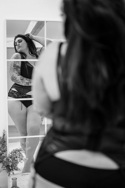 Sinnliches Dessousfoto einer kurvigen Frau in schwarzer Lingerie vor dem Spiegel